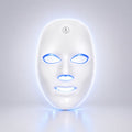 A white LED light therapy face mask with glowing blue and white light accents around the eye, nose, and mouth cutouts, shown on a clean light gray background.
