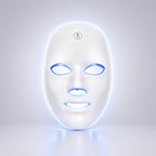 A white LED light therapy face mask with glowing blue and white light accents around the eye, nose, and mouth cutouts, shown on a clean light gray background.
