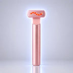 A rose gold handheld beauty device with a glowing red wavy light on its head, standing upright on a reflective surface against a light gray background.