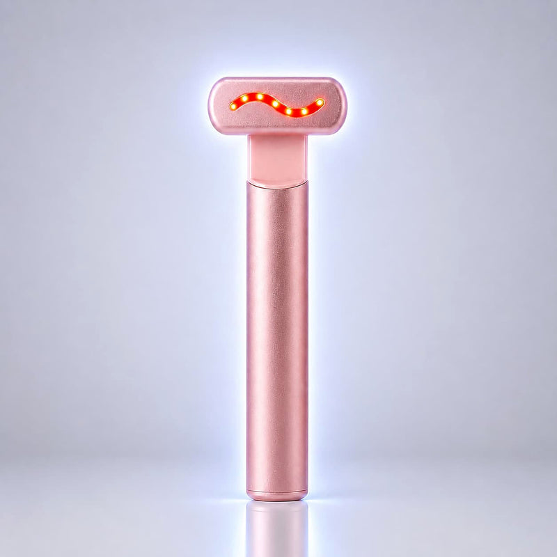 A rose gold handheld beauty device with a glowing red wavy light on its head, standing upright on a reflective surface against a light gray background.
